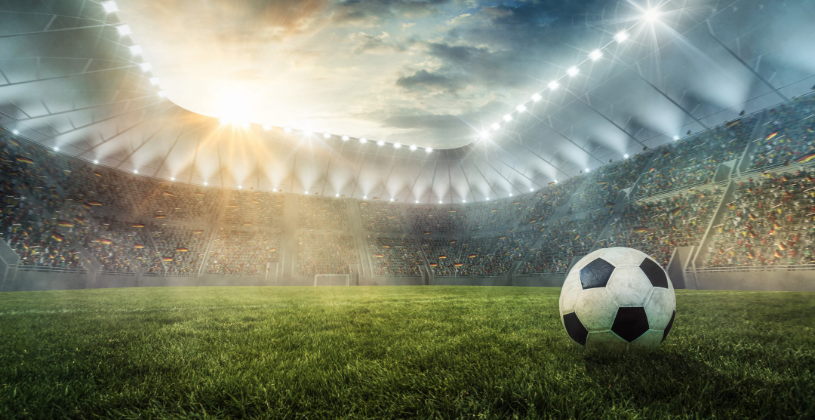 Imagem mostrando bola em gramado de estádio de futebol